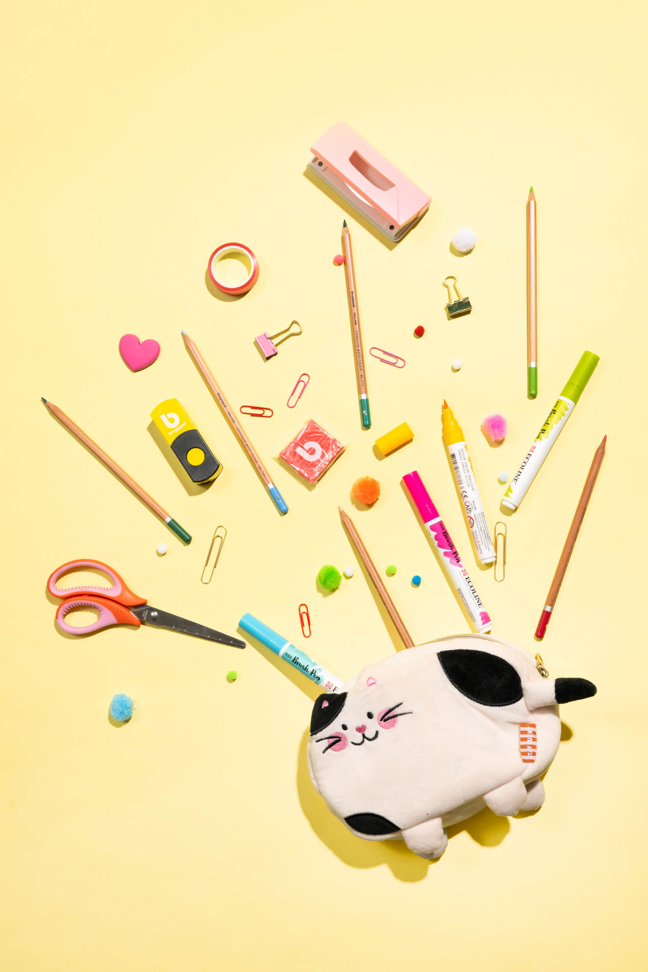 Flatlay met stiften, potloden en etui op geel