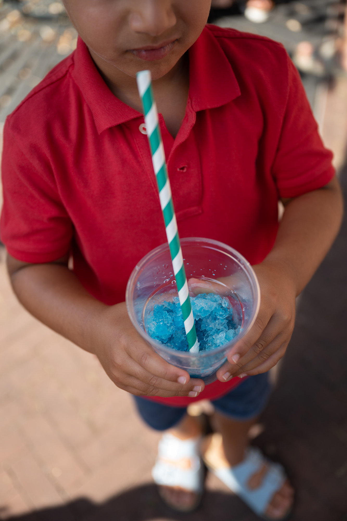 Kind in rood shirt drinkt een blauw schaafijsje, project De Vormforensen