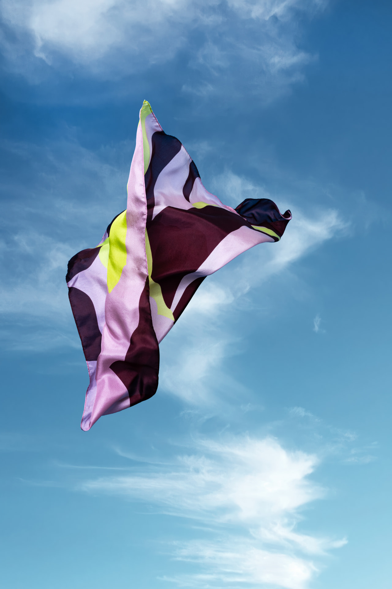 Roze-bordeaux sjaal wappert in de wind tegen de lucht