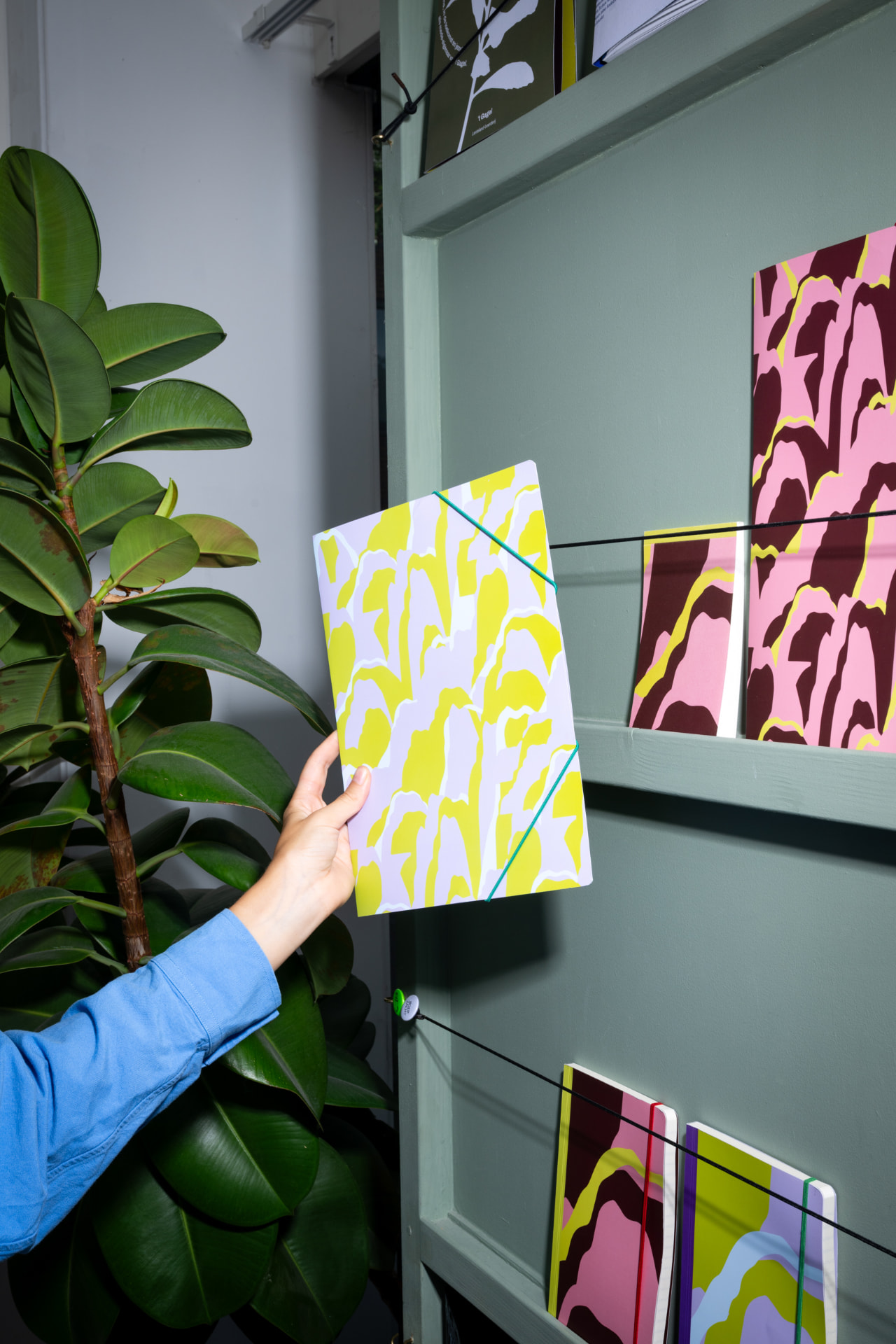 Hand pakt een geel-wit schrift uit het winkelrek