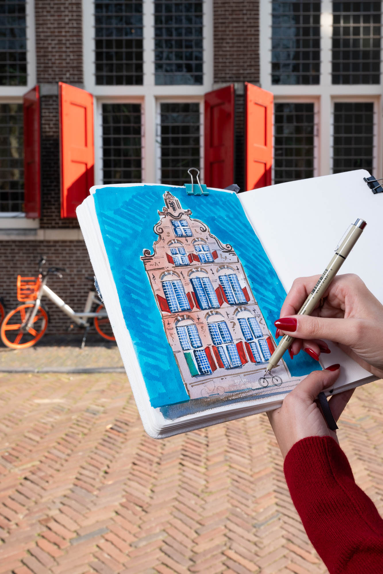 Aquarel van grachtenpand met rode luiken in Amsterdam