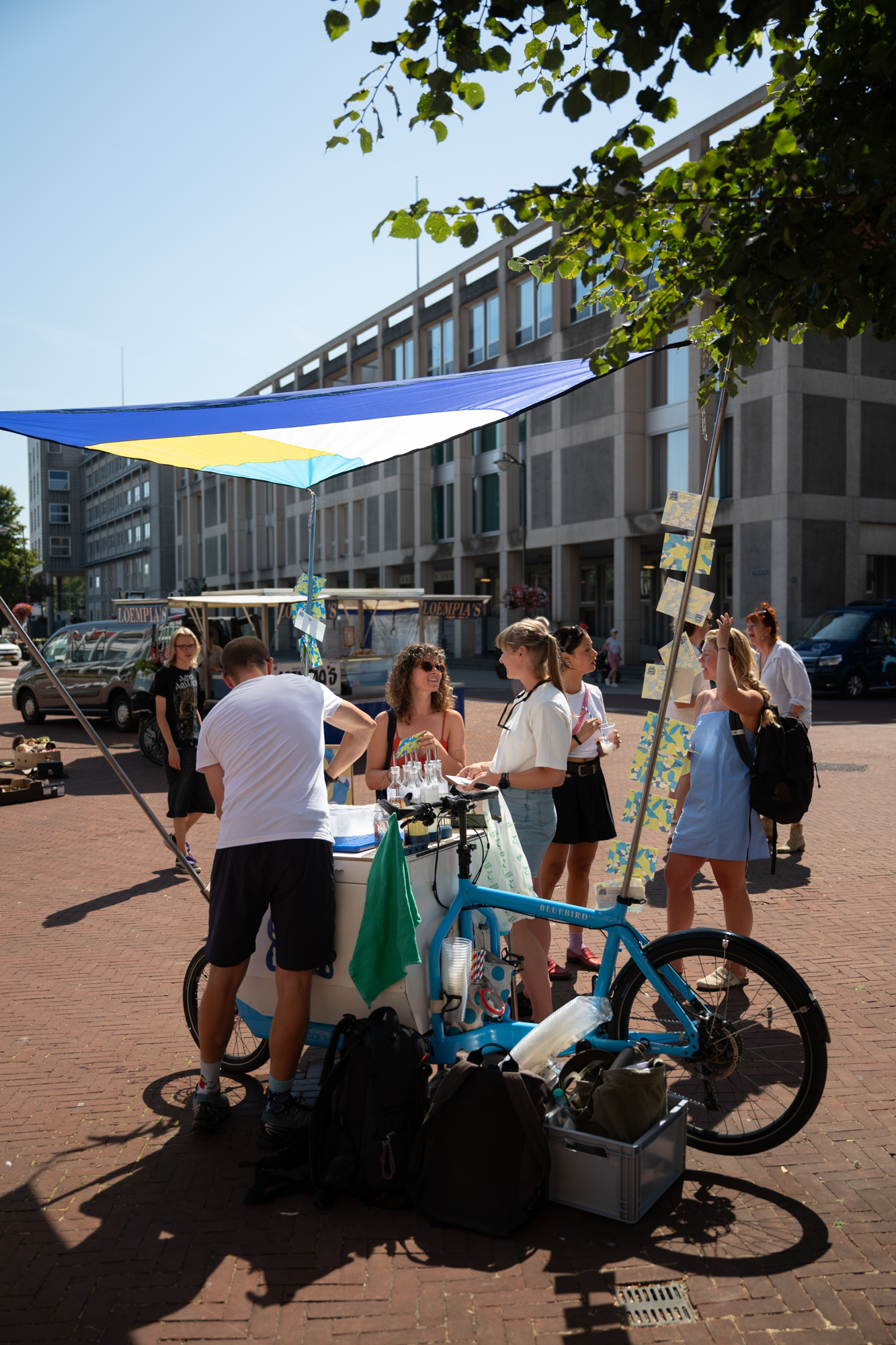 Bezoekers bij de ijsfiets van Het Smeltloket onder een blauw-geel schaduwdoek, project De Vormforensen