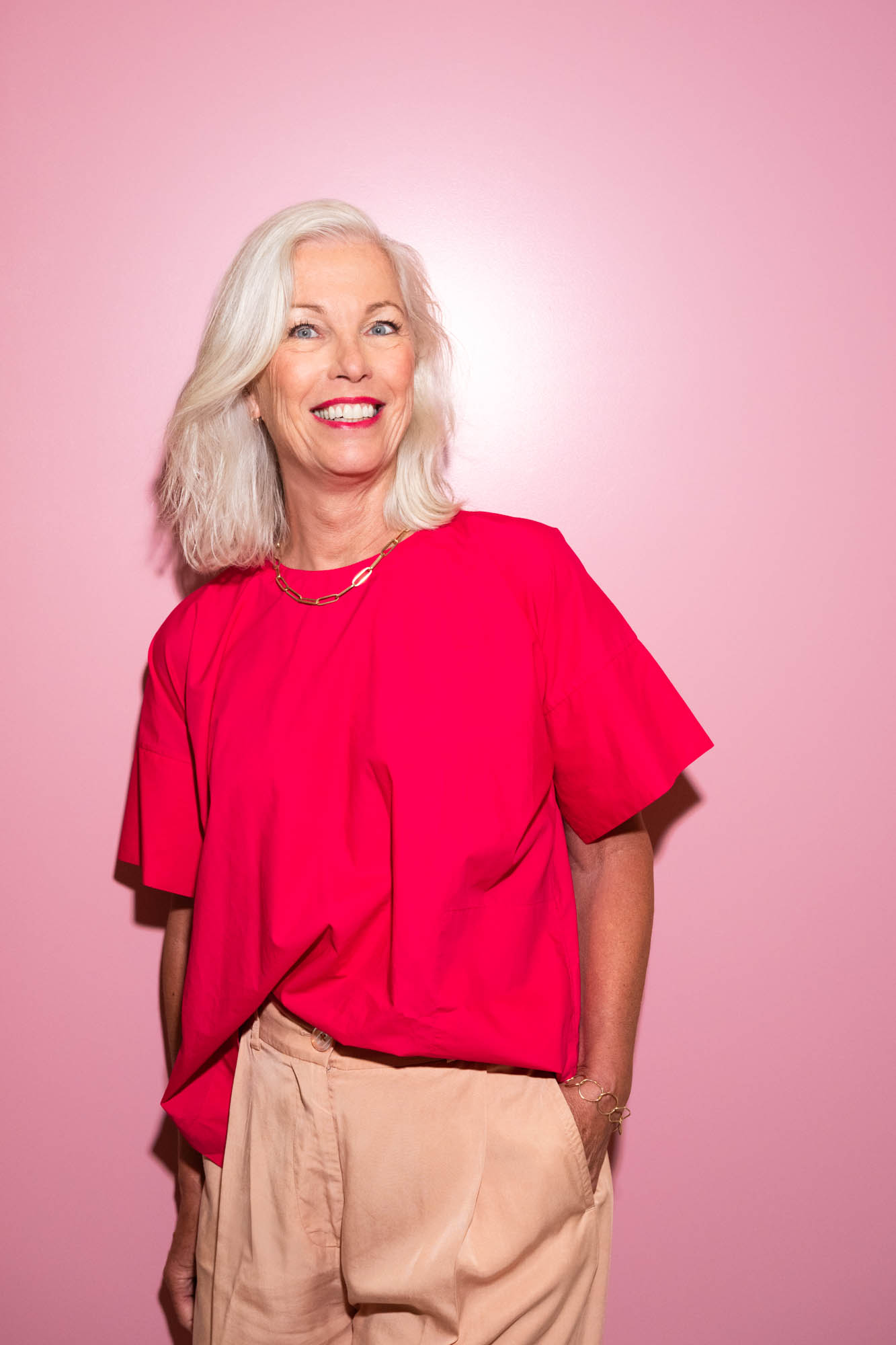 Portret van medewerker in rood tegen roze achtergrond