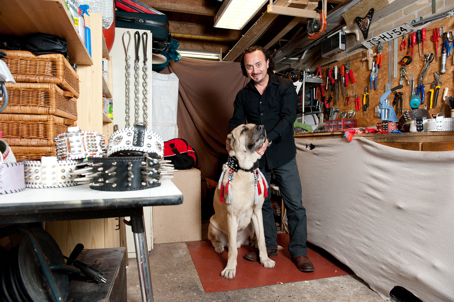 Portret hondenhalsbandenmaker met hond in werkplaats